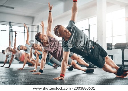 Gym class, group and athletes doing a workout for fitness, health or wellness flexibility. Sports, community and people doing a side plank exercise, training or challenge together in a sport studio. Royalty-Free Stock Photo #2303880631