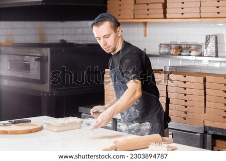 Dough for pizza, the chef rolls out the blanks. Closeup hand of chef baker in uniform white apron cook pizza at kitchen
