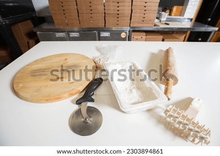 A kitchen tool for making dough. Dough for pizza, the chef rolls out the blanks. Closeup hand of chef baker in uniform white apron cook pizza at kitchen