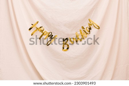 Happy birthday wallpaper with gold text on light fabric background. Birthday party decoration. Minimal creative natural concept.