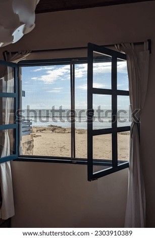 An open window of a beach house against the background of the sea against the background of a sunny autumn day