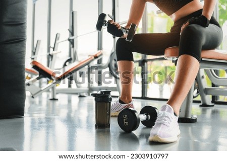 Woman fitness training an exercise class in the gym. Weight lifting or holding dumbbells for beginners. Fitness exercise building muscle, Lifestyle and health of women concept. Royalty-Free Stock Photo #2303910797