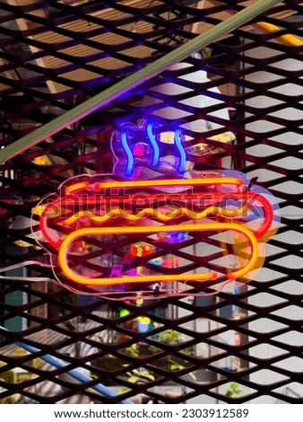 Illuminated Hot Dog. Bright colored collection of symbols or sign boards glowing with colorful neon light for cafe, restaurant, motel or cocktail bar. Template layout on grid background, copy space.