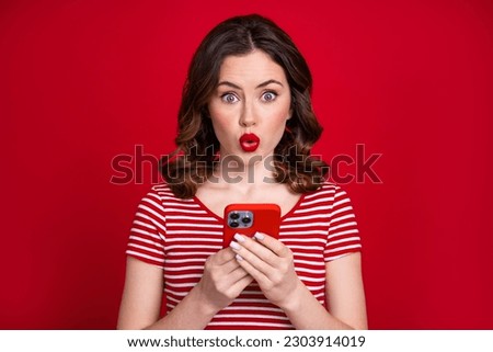 Photo of impressed gorgeous girl pouted lips hold use smart phone isolated on vivid red color background