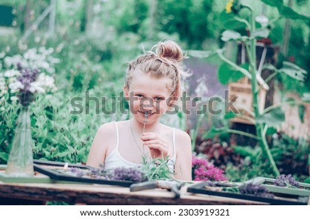 adorable blond girl sitting in the garden and creating lavender framed images