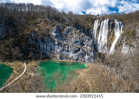 Colorful spring panorama with beautiful view of waterfalls and lake along with turquoise water and sunshine in Plitvice Lakes National Park. Lake and waterfall shine by sunlight. Croatia. Europe.  Royalty-Free Stock Photo #2303921415