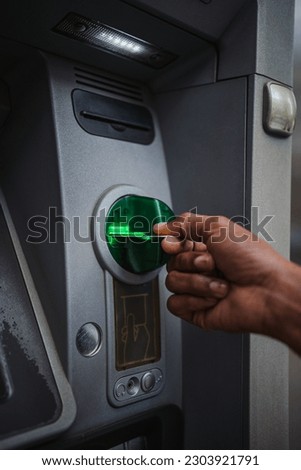 Close up shot of a man inserting a credit card in an ATM outdoors to check the bank account. Royalty-Free Stock Photo #2303921791