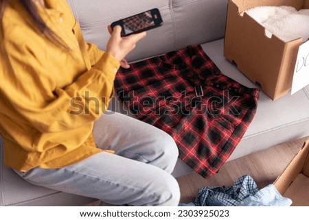 Woman taking photo of skirt at home on smartphone camera for post to sell online on internet market website, selling online ecommerce. Close-up