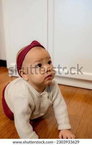 A baby girl sitting on the floor, playing with teething toy.