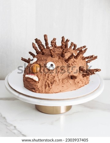 Funny ugly hedgehog cake for children's birthday made of chocolate and sweets Royalty-Free Stock Photo #2303937405