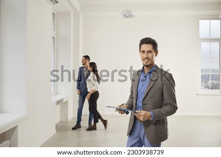 Young happy couple looking a new house with realtor. Professional real estate agent shows bright new apartment. Successful family ready to become homeowners. Real estate market concept. Royalty-Free Stock Photo #2303938739