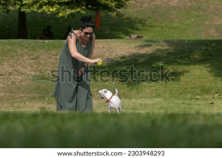 Woman walking with a white terrier dog outside on a summer day