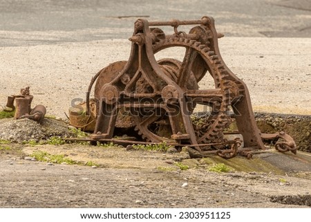 A rusty old winch in a harbour used to help pull boats and creels up from the water