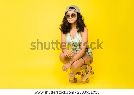 Hispanic teen girl having fun roller skating using vintage roller skates and summer sunglasses next to yellow copy space