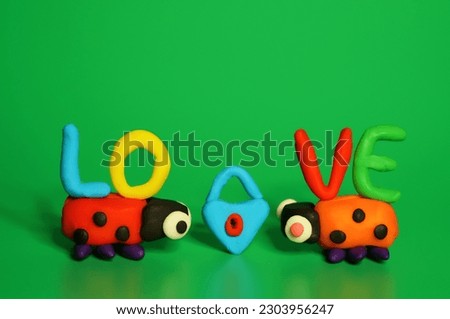 Two toy ladybugs look at each other. There's a lock between them. Green background. Decorations for Valentine's Day.