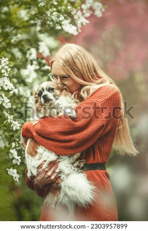 Portrait of a young blonde woman and her cute chihuahua dog in spring in a park outdoors