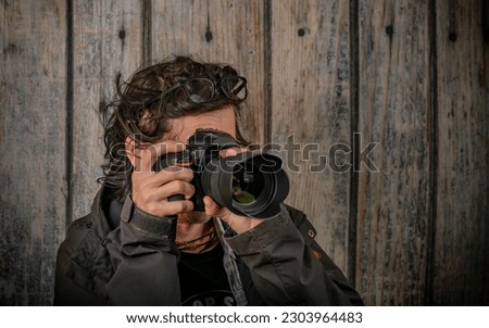 Male with black full frame camera and wide angle lens near wooden old wall