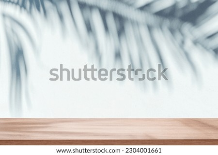 Blurred shadow of tropical palm leaves on gray wall and table top in the foreground. Summer concept.