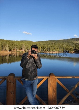 A photographer taking a photo of a lake with mountains in the background.