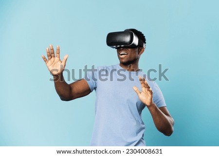 Smiling african man playing video game in VR glasses isolated on blue background. Excited male gamer, VR reality concept