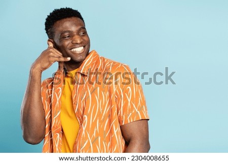 Portrait of handsome nigerian man showing hand gesture call on phone isolated on blue background. Smiling male looking away, copy space, place for advertising