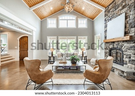 Living room interior with vaulted ceiling with wood cedar panelling stone fireplace brown leather armchairs coffee table and area rug natural brown tones Royalty-Free Stock Photo #2304013113