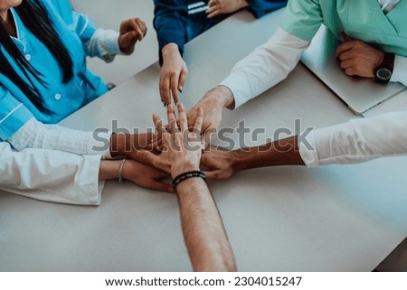 A group of doctors and a medical nurse join their hands together on a table, showcasing the unwavering teamwork and solidarity that drives their collective efforts in the healthcare field Royalty-Free Stock Photo #2304015247