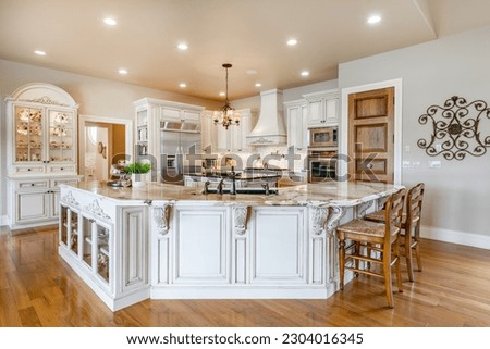 Elegant french country style kitchen with blue cast iron oven marbled countertops soft yellow wood cupboards gleaming hardwood floors  Royalty-Free Stock Photo #2304016345