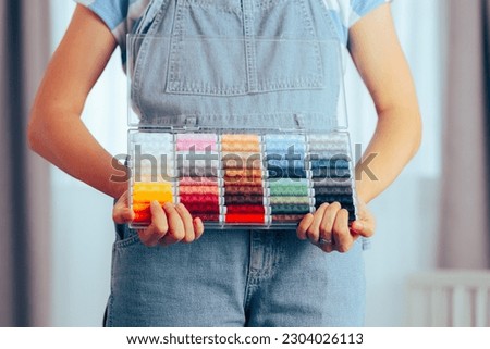 
Hands Holding a Box of Sewing Thread Colorful Set. Detail of a person presenting her spool collection for dressmaking 

