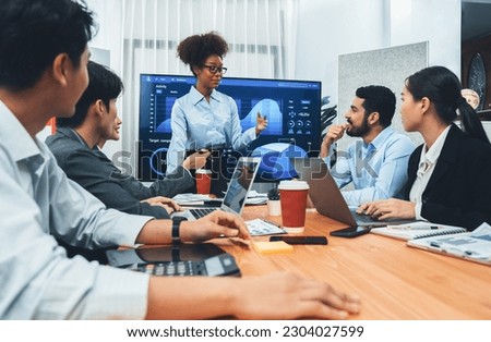 Young african businesswoman presenting data analysis dashboard on TV screen in modern meeting. Business presentation with group of business people in conference room. Concord Royalty-Free Stock Photo #2304027599