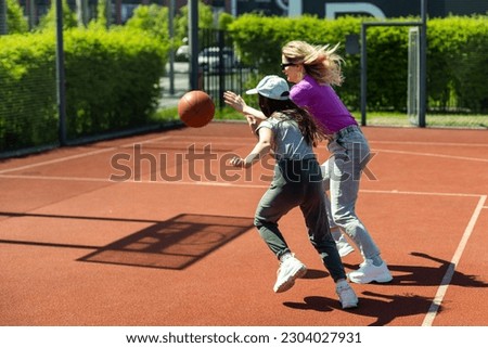 Mother and daughter playing basketball.