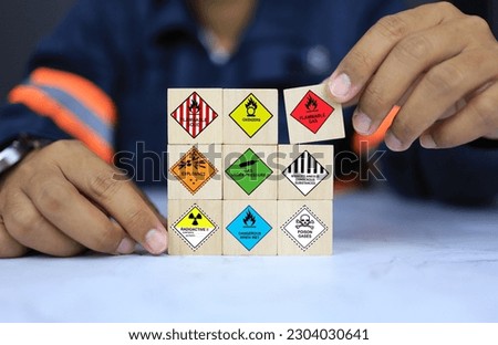 Security officers arrange dangerous warning sign icon on wooden cube for operator safety such as explosions, radioactive, toxic gases, etc. Royalty-Free Stock Photo #2304030641