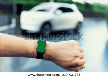 Focus mockup smartwatch with green screen for hologram or interface copyspace of electric car battery that recharging at charging station. Progressive mockup device mockup with green screen.