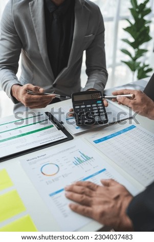 Businessman using calculator to calculate company financial statements with colleagues have an analysis Discuss documents and work together to solve problems within the company. Royalty-Free Stock Photo #2304037483