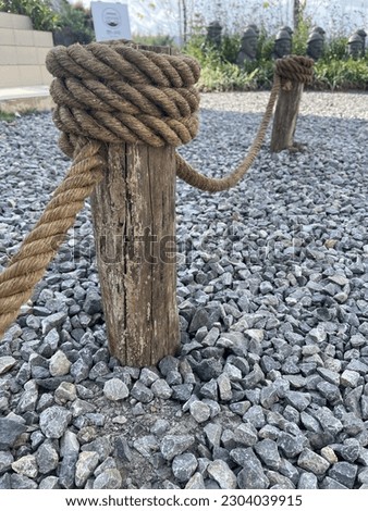A wooden pole with a large rope wrapped around it as a line.