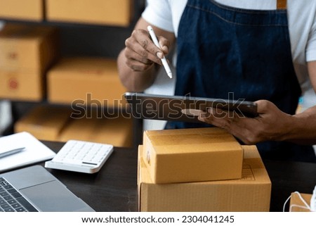 Freelance businessman checking and verifying shipping information Package boxes to prepare for delivery to customers who order online on laptop computers and tablets. ecommerce startup business ideas Royalty-Free Stock Photo #2304041245