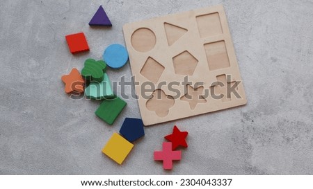 Wood Puzzle with Geometric Shapes. Wooden kids geometric puzzle with the object removed and surrounding puzzle. Montessori wooden toys for children. Sorter for different shapes. Royalty-Free Stock Photo #2304043337