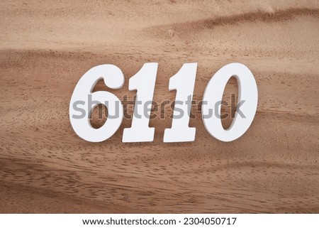 White number 6110 on a brown and light brown wooden background.