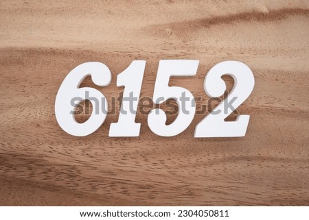 White number 6152 on a brown and light brown wooden background.