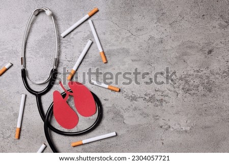 Quit smoking for better health concept. A pack of cigarette with red lungs paper shape and stethoscope on gray background. Copy Space.