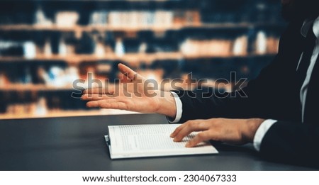 Black suit-clad businessman or lawyer studying law book background of school library, concept of professionalism and success in MBA or law degree. Equilibrium