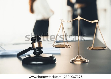 Balanced scale of justice and gavel hammer in focus on blurred background of lawyer colleagues discuss and plan for lawsuit in law firm office, as legal representatives. Equilibrium Royalty-Free Stock Photo #2304067395