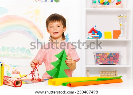 Happy boy holding  beads and carton Xmas tree