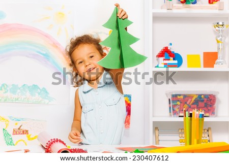 Girl holding carton Xmas tree standing at table