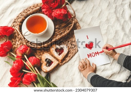 The child draws a card for mother's day for mom, a festive concert.