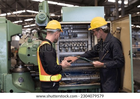 Group of male electrician worker checking, repair, maintenance electric system of CNC machine in factory. Team of male electrician engineer inspecting quality electric during manufacturing process Royalty-Free Stock Photo #2304079579