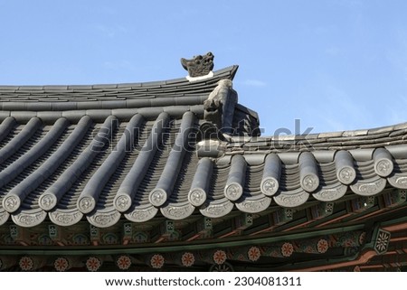 Low angle view of eaves and tile roof of Junmyeongdang House against blue sky at Deoksugung Palace, Seoul, South Korea

