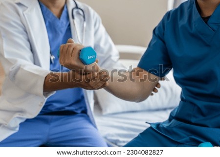 Using dumbbell, Physiotherapy specialists help patients in physiotherapy. about Muscle Weakness and Fatigue Royalty-Free Stock Photo #2304082827