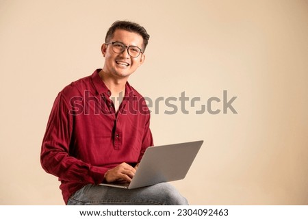 Simple young freelancer sitting working on laptop pc computer looking isolated on bright colored wall, studio photo background. 
