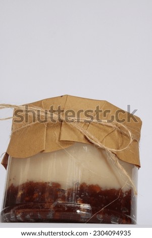 sweets jar of three layers chocolate and cream and coffee with whits background, on the floor or held on hand covered with brown wrapping paper